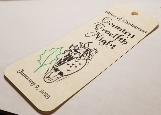 a photo of a bookmark that was given out at a special event. The bookmark was made by printing the design
		(an owl in a jester crown) on 'parchment' cardstock, then a laser engraver was used to cut each individual bookmark out of the sheet, including the
		hole for the tassel.