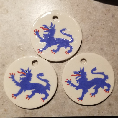 Three ceramic medallions, each painted with a blue tyger passant