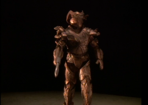 Still frame from Star Trek: Deep Space Nine Season 5, episode 18, featuring a gold/bronze colored target droid marching towards the camera.