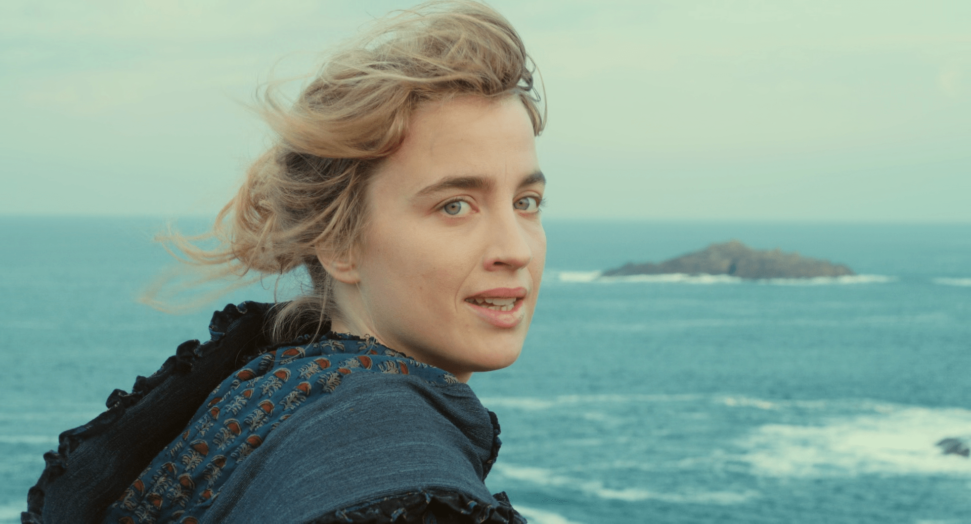 still from Portrait of a Lady on Fire; Adèle Haenel as Héloïse looks at the camera with the ocean in the background